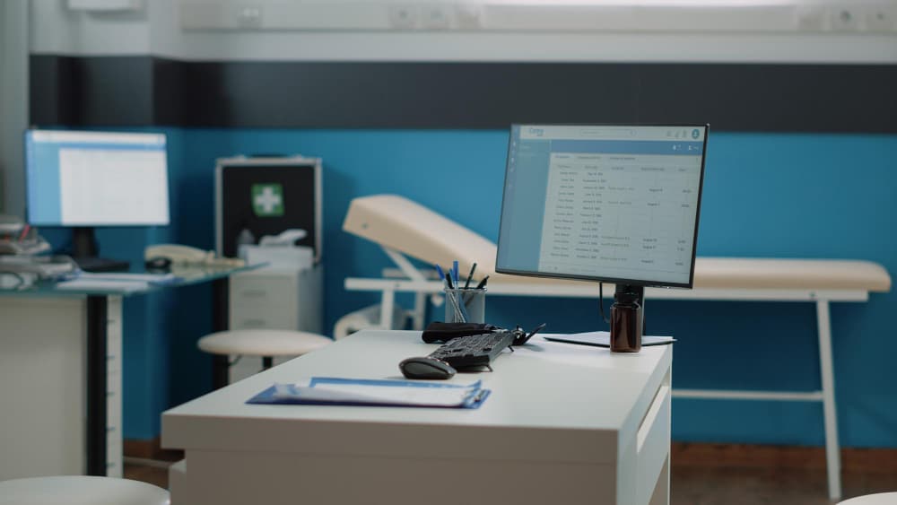 A clean medical clinic Wilmington Delaware room with a desk, computer, and exam table.