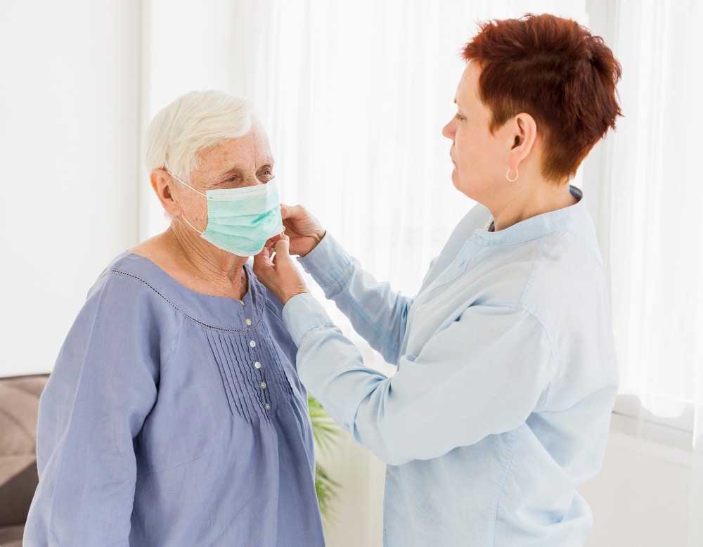 Caregiver assisting senior woman with face mask, Autoimmune Disease Care Dover Delaware.